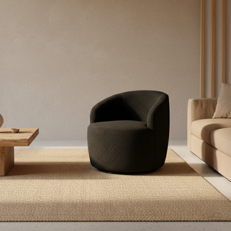 Black Boucle Swivel Chair in a minimalistic room with a textured wall and stone sculpture.