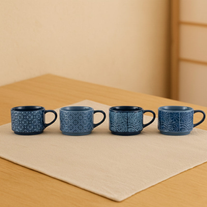 Four Blue Coffee Mugs with decorative patterns on a beige background