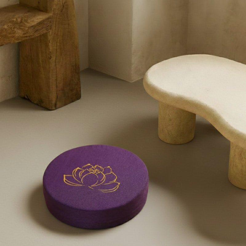 Purple Lotus Meditation Cushion on a beige floor next to a stone bench.