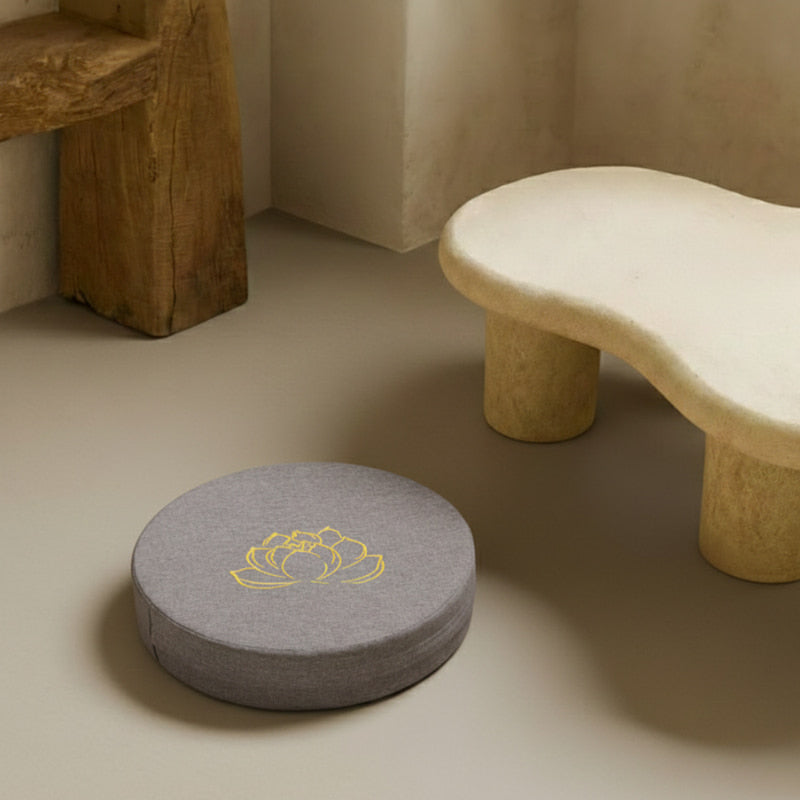 best meditation cushion with a yellow lotus design on a beige floor next to a stone bench.