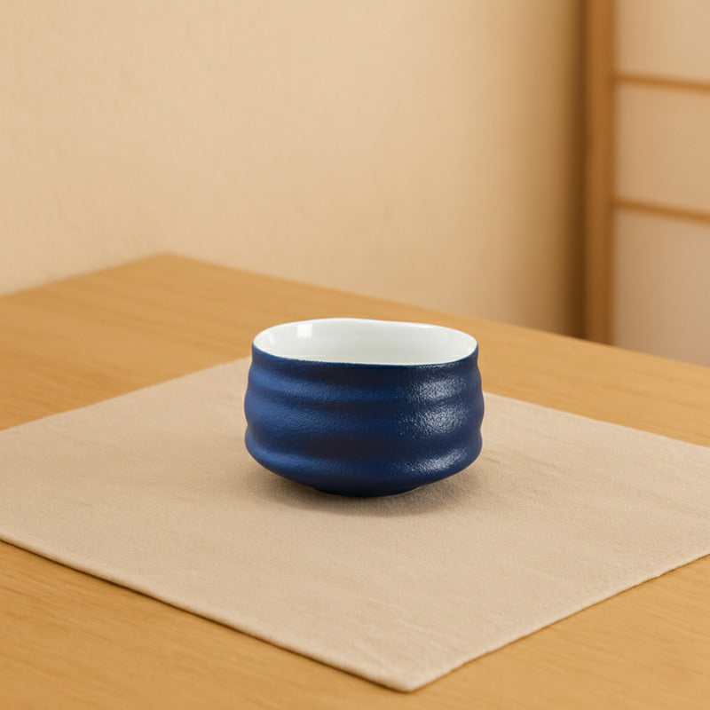 Blue matcha bowl with white interior on a brown background