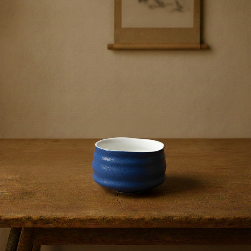 Blue tea bowl design on a wooden table with a beige wall in the background