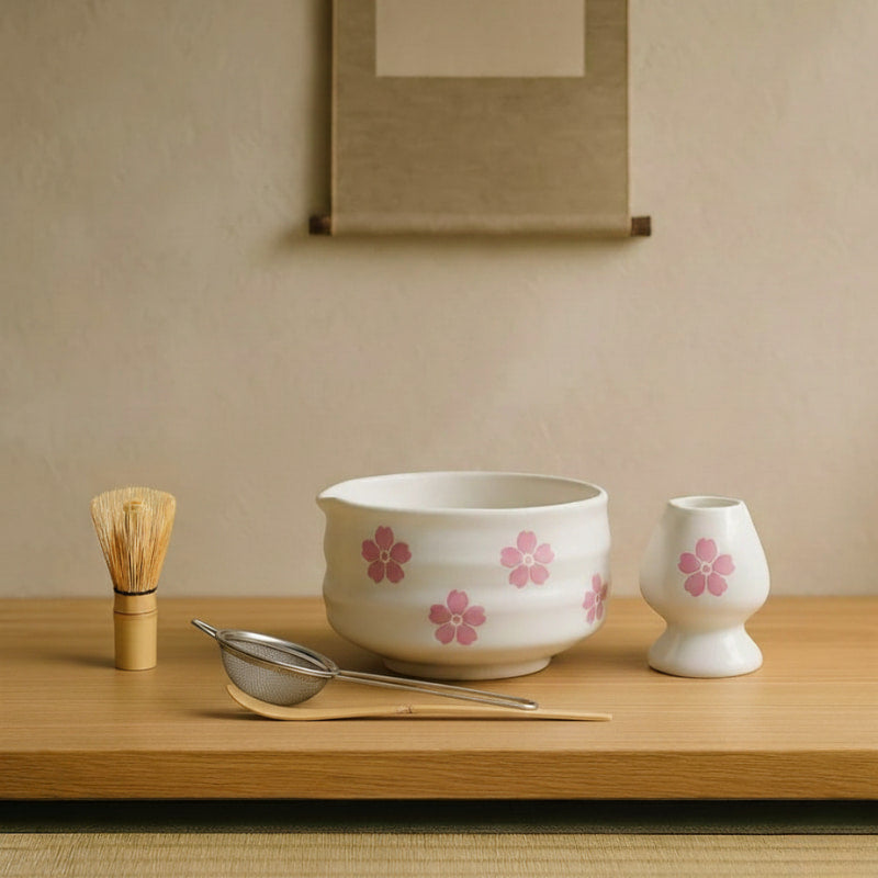 Tea-making ceramic design heritage set with a bowl, whisk, and small cup on a wooden tray against a beige wall.