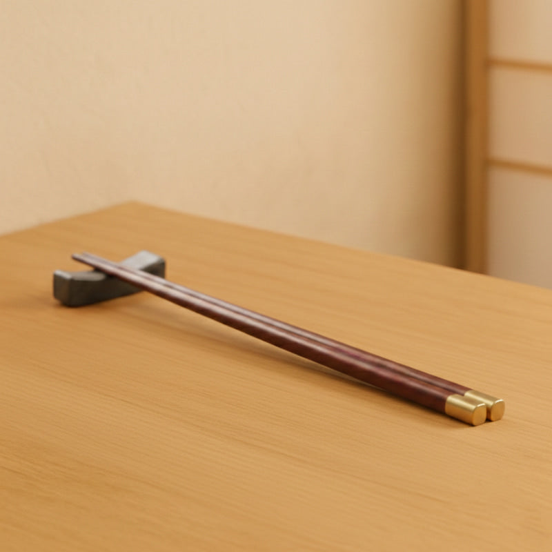 Wooden chopsticks set with gold accents on a beige napkin over a wooden surface