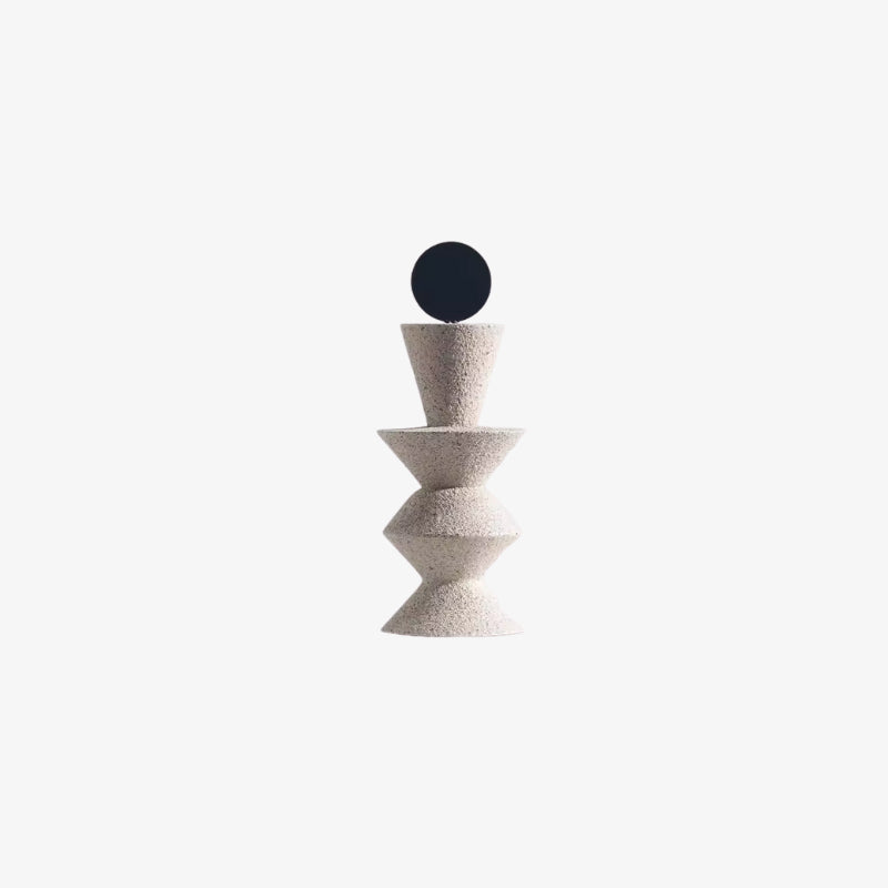 Decorative circle object with a black sphere on top of a textured beige column against a white background