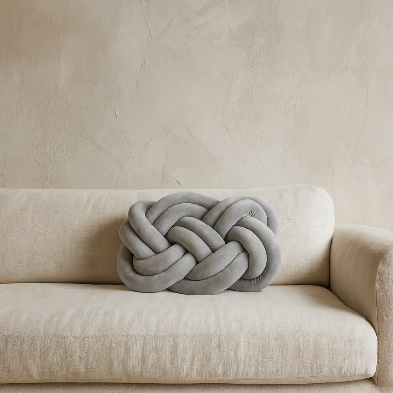 Gray design cushion pillow on a beige sofa against a beige wall