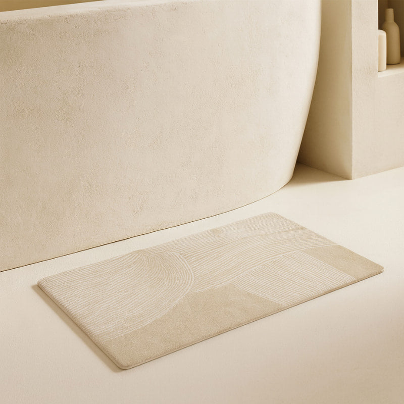 Beige fast drying bathroom mat
next to a bathtub.