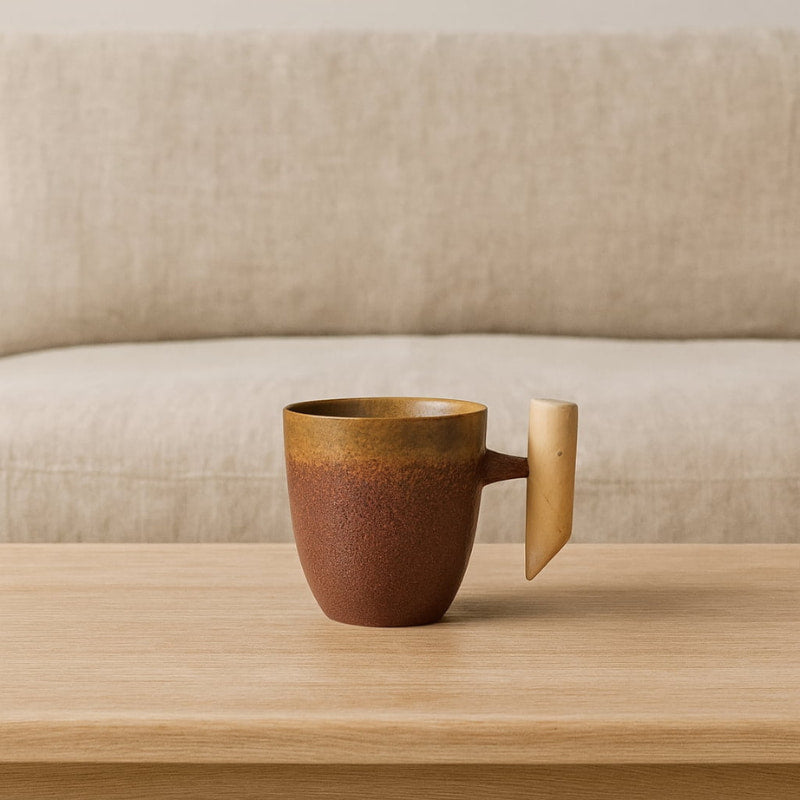 japanese ceramic tea cup with wooden handle on a wooden surface with a beige sofa in the background