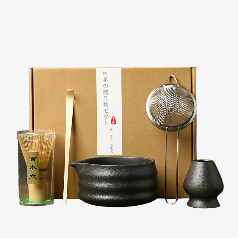matcha set black friday with a black bowl, whisk, spoon, and strainer in front of a brown box.