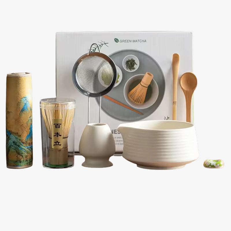Matcha set with bowls, cups, and tools in front of a branded box on a white background