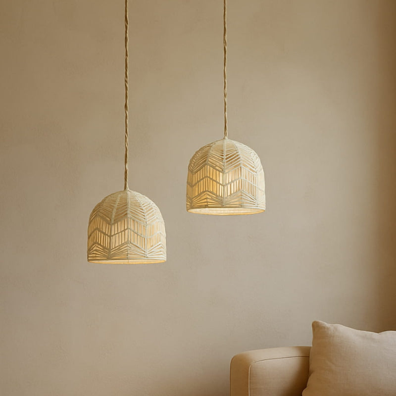 Two minimalist wabi sabi lights hanging against a beige wall with a couch in the corner.