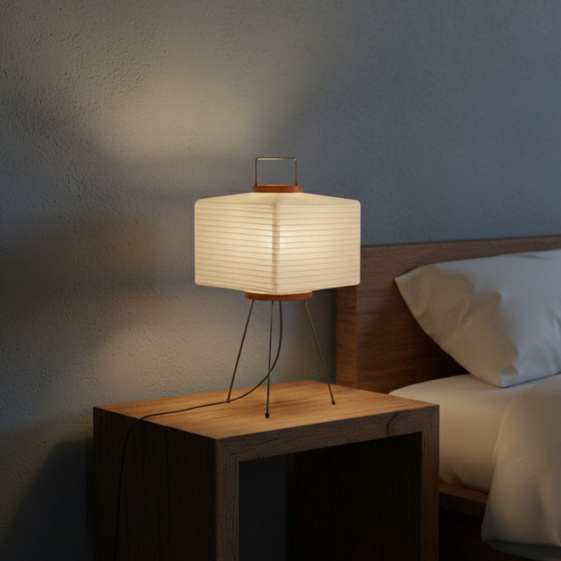 Modern paper floor lamp on a wooden nightstand next to a bed in a bedroom setting