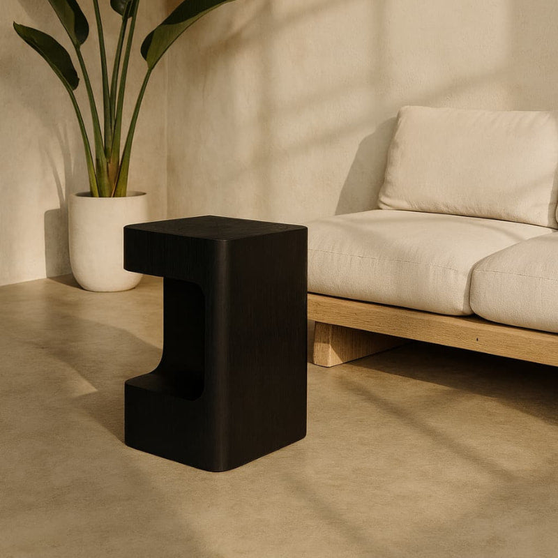 Black small wood stools or side table in a room with a beige sofa and plant