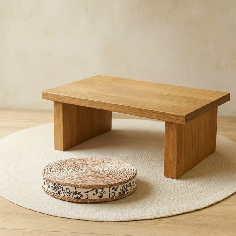 Wooden low table with a round tea ceremony cushion on a wooden floor.