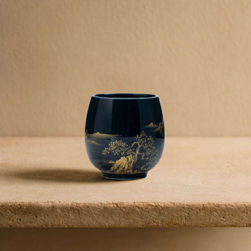Blue tea cup handmade with gold floral design on a wooden surface with a warm light background