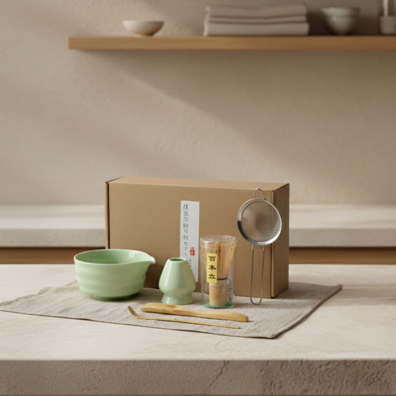 traditional chinese tea making set with green bowls, a box, and tea accessories on a wooden surface.