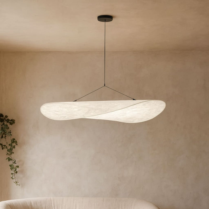 Modern Wabi Sabi style pendant light in a room with a neutral wall and plant.