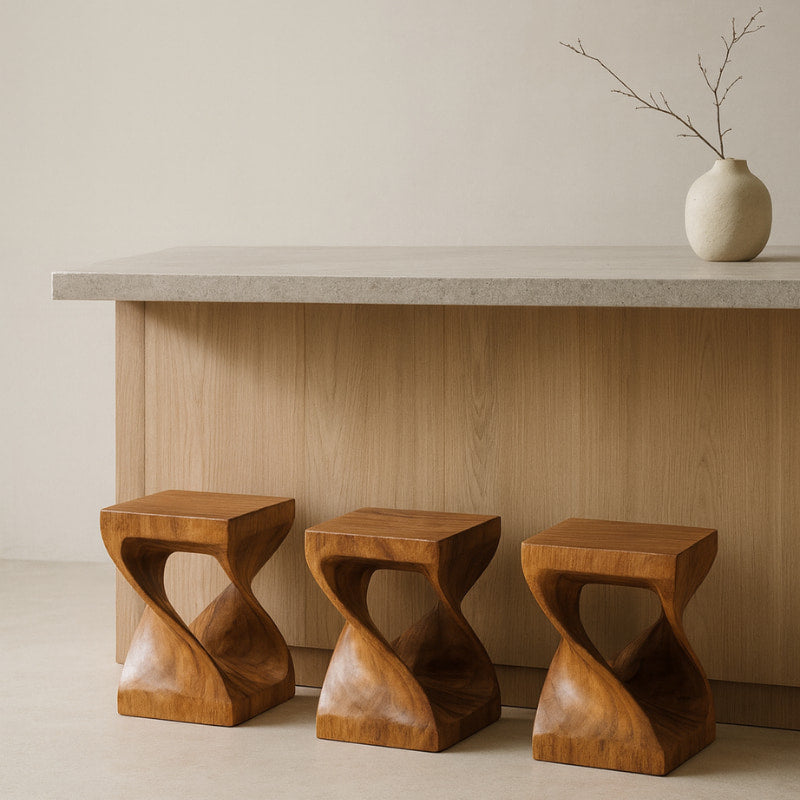 Three wooden bar stools in front of a light-colored wall with a vase on a surface.