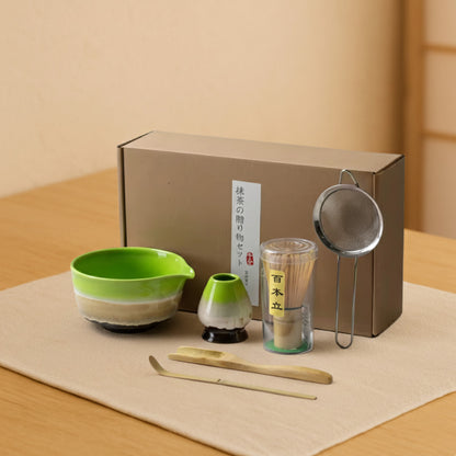 Ceramic Matcha Set with a green bowl, strainer, and other tools on a wooden surface.