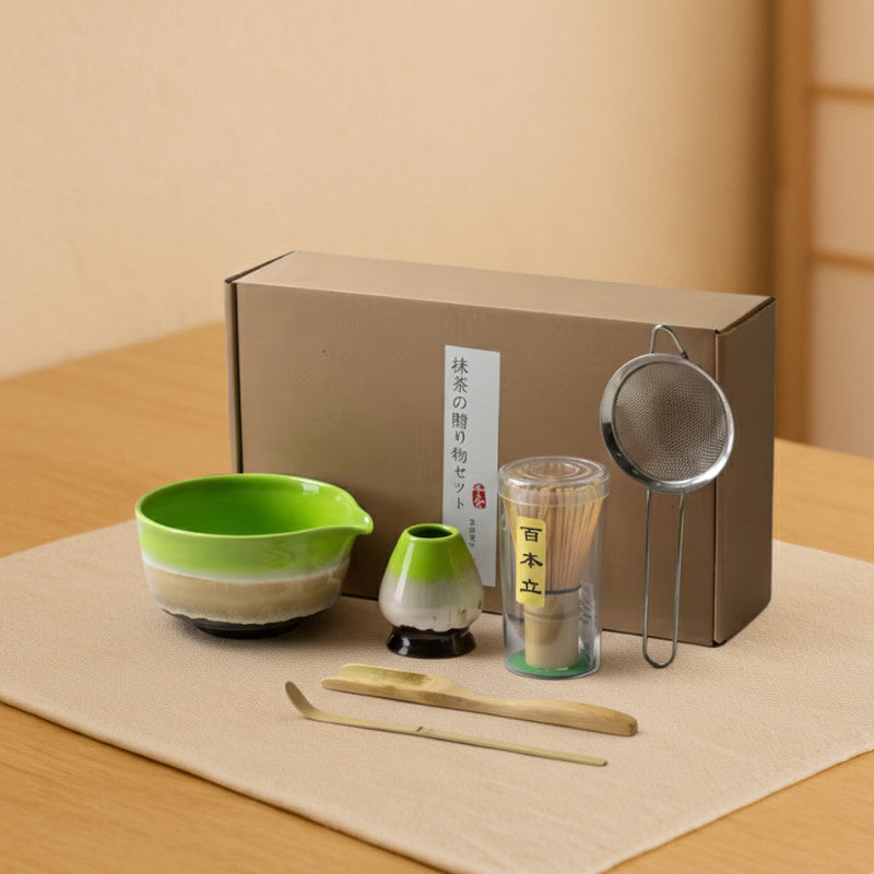 Ceramic Matcha Set with a green bowl, strainer, and other tools on a wooden surface.