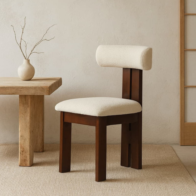 Lounge Chair wabi sabi with white cushion next to a wooden table with a vase on a neutral background