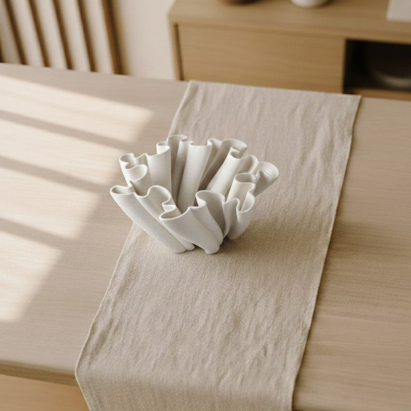 White Modern Minimalist Vase on a beige table runner with a wooden surface in the background