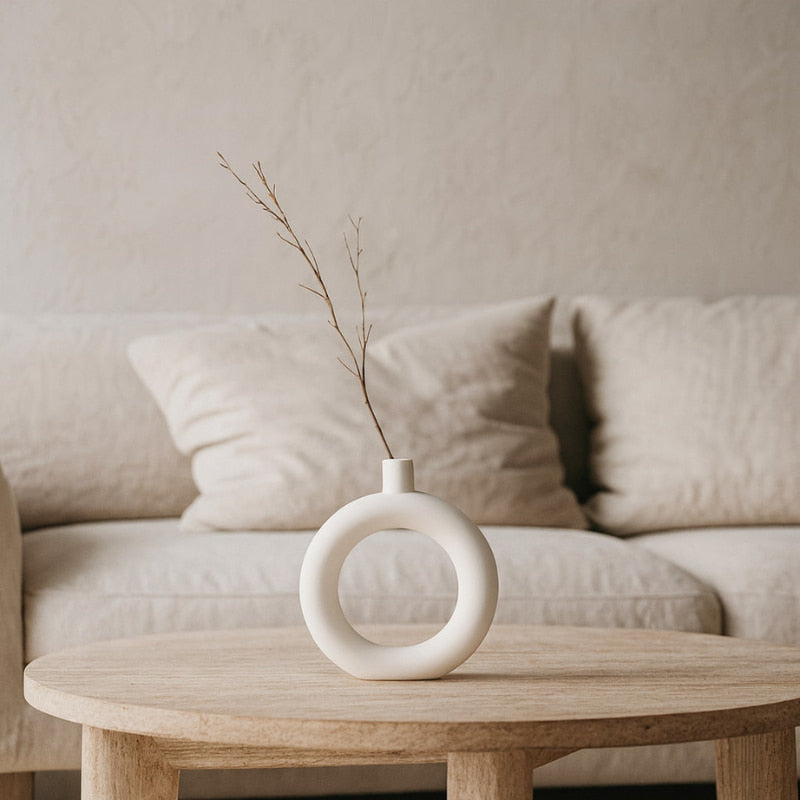 Wabi sabi ceramic pot with branches on a wooden coffee table in a living room setting.