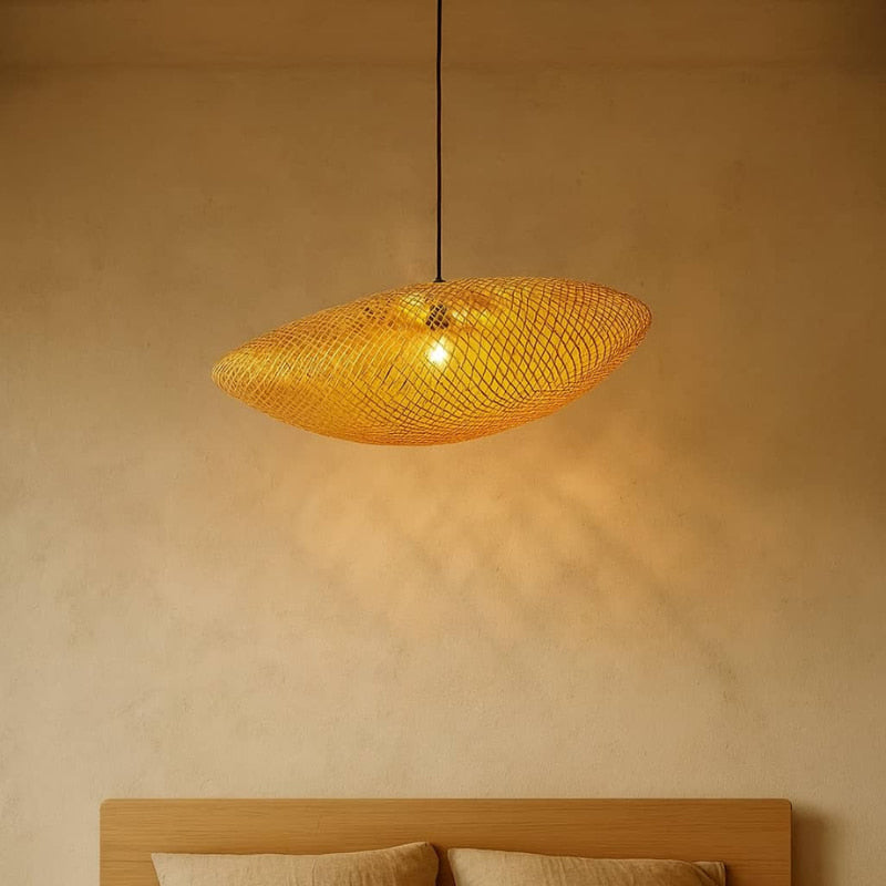 Woven pendant light hanging above a bed in a room with warm lighting.