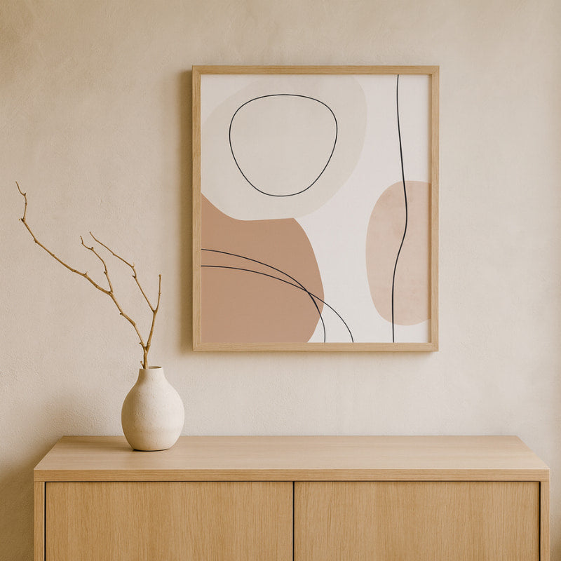 Abstract wabi sabi art​ on a wall above a wooden cabinet with a vase.