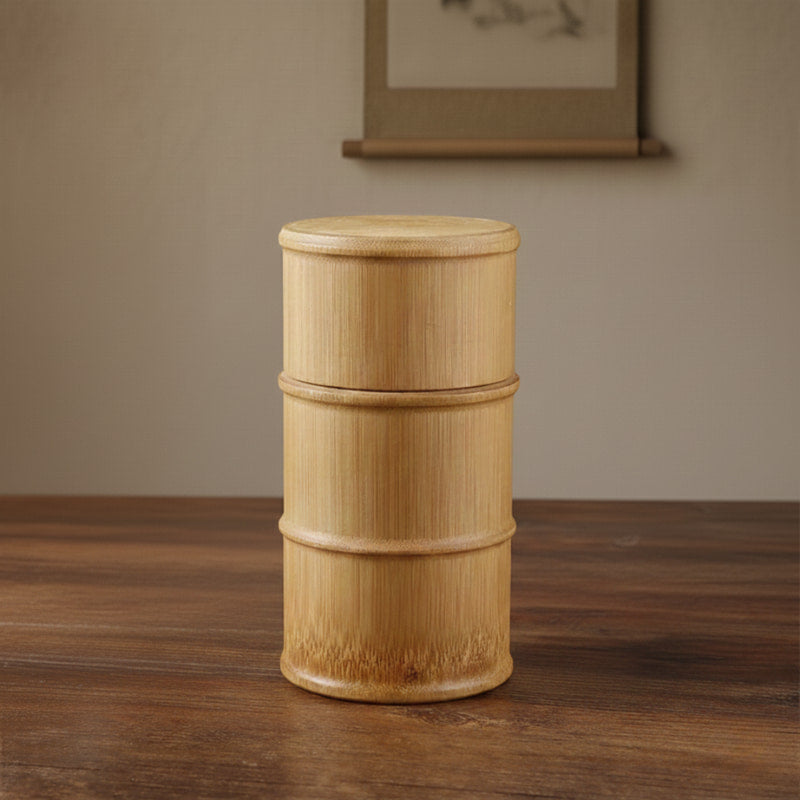 Wooden cylindrical bamboo tea container on a wooden surface with a neutral background