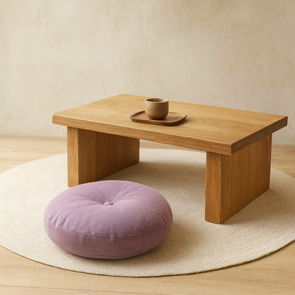 Wooden table with a cup and tray on a beige rug, with a purple bench cushions in the foreground.