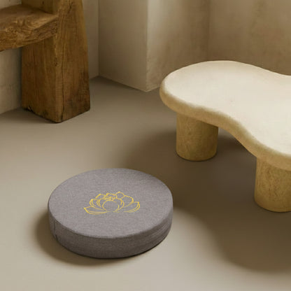 best meditation cushion​ with a yellow lotus design on a beige floor next to a stone bench.
