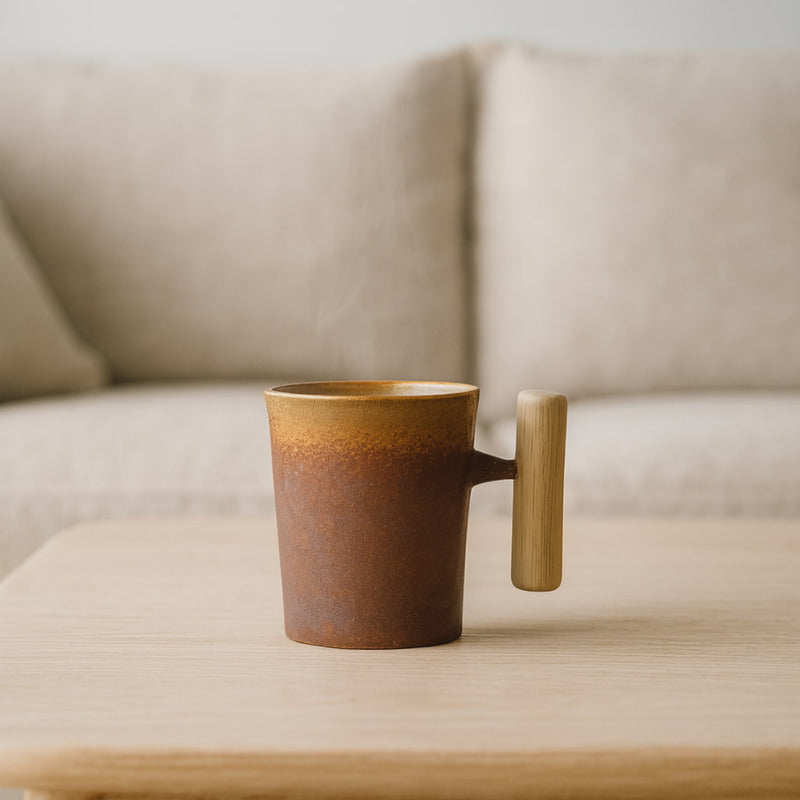 ceramic japanese tea cup​ with a handle on a wooden surface in front of a beige sofa.