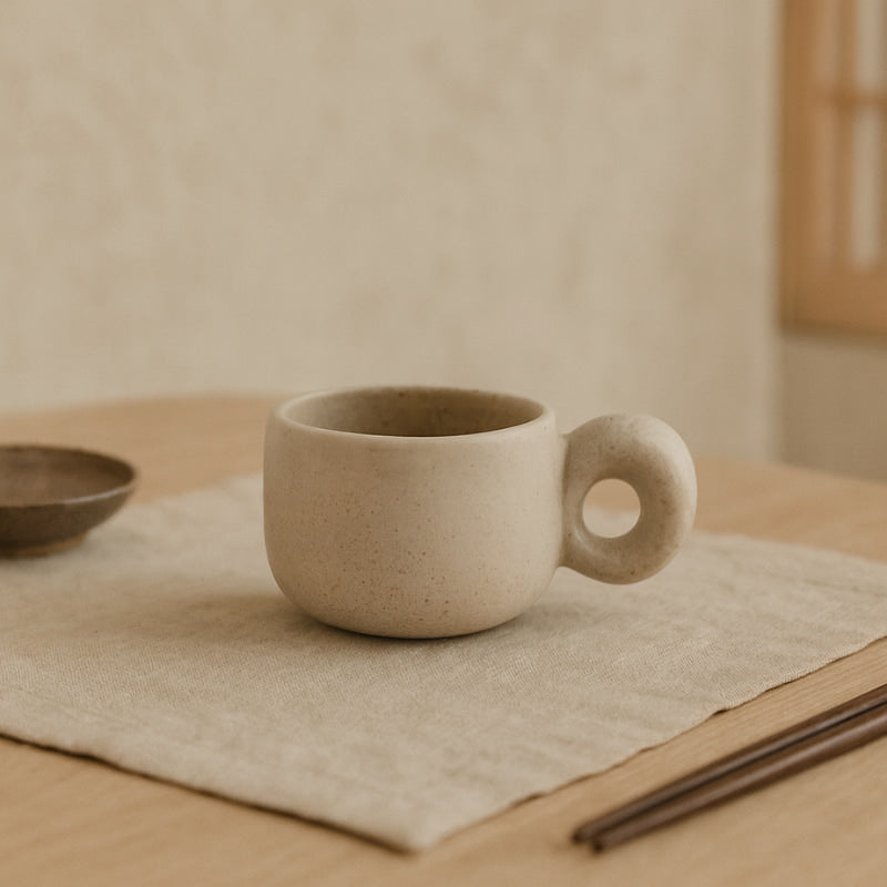 Ceramic mugs​ with a unique handle on a wooden table with a neutral background