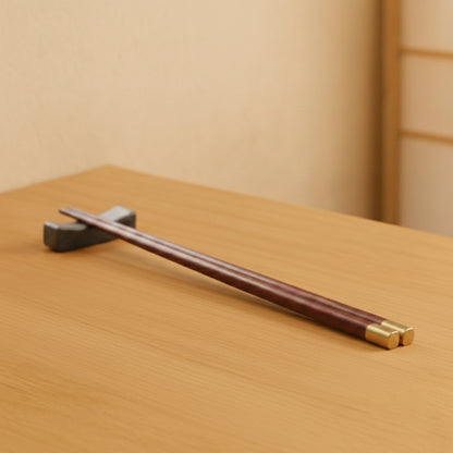 Wooden chopsticks set with gold accents on a beige napkin over a wooden surface