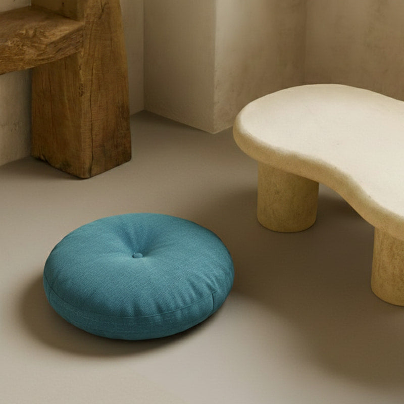 Blue cotton floor cushion on a beige floor next to a stone bench