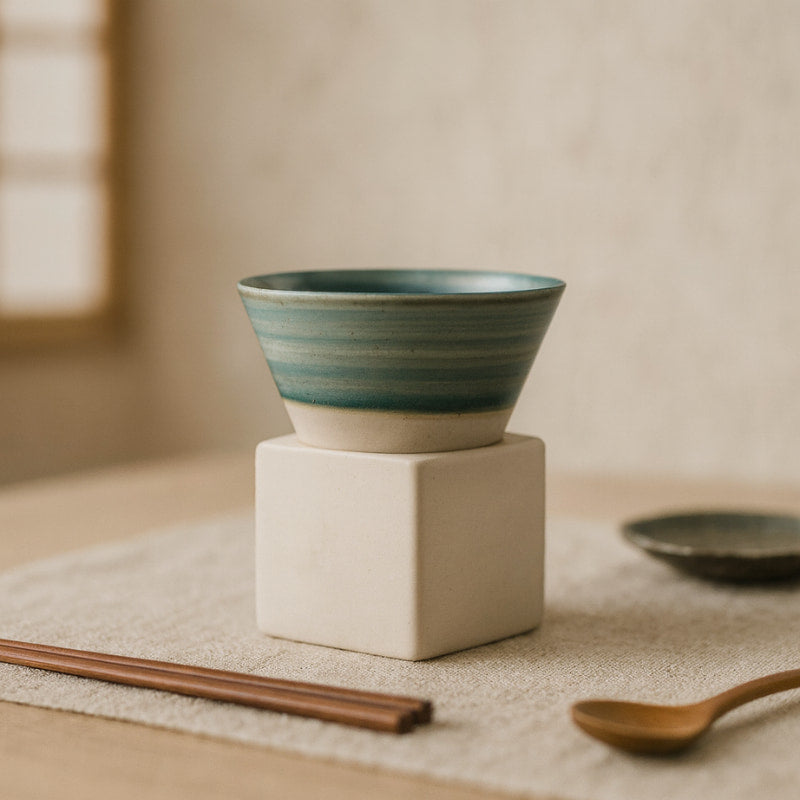cup of coffee blue​ on a white block, with a wooden spoon and chopsticks on a neutral background.