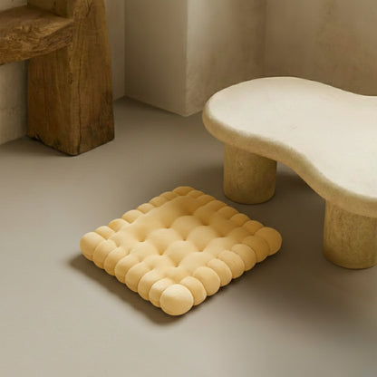 Yellow cushion seating floor and stone-like table with a bowl on a neutral background