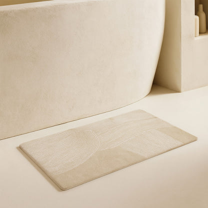 Beige fast drying bathroom mat
​ next to a bathtub.