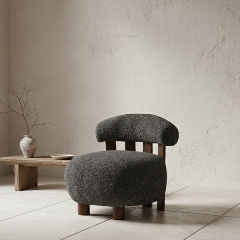 gray boucle chair​ with wooden legs in a minimalistic room.
