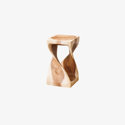 handmade wooden stool in front of a wooden desk with a vase on a neutral background