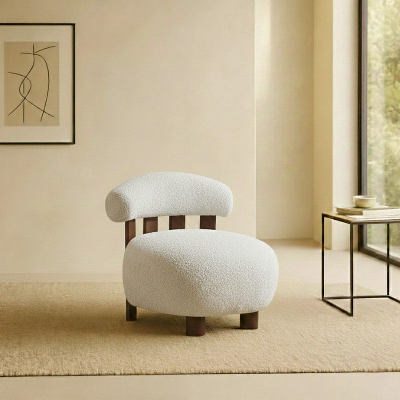 White japandi accent chair in a room with a abstract painting on the wall and a side table.
