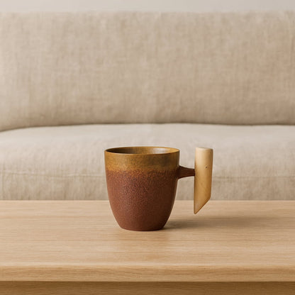 japanese ceramic tea cup​ with wooden handle on a wooden surface with a beige sofa in the background