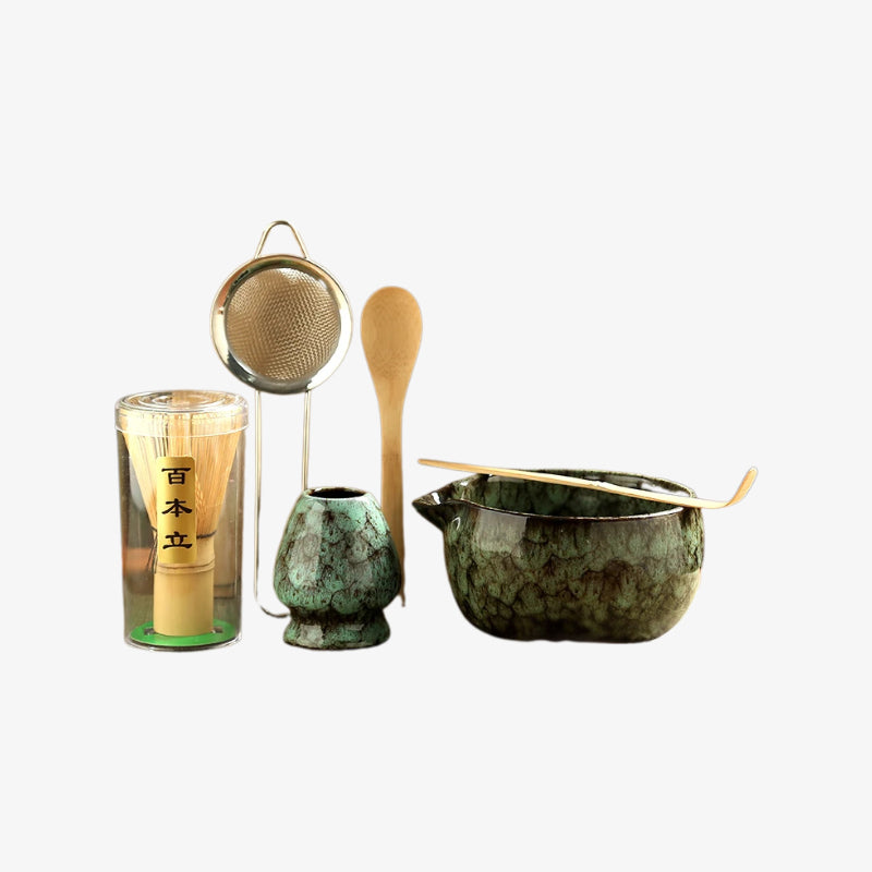 japanese matcha ceremony set​ with green ceramic pot, wooden spoon, and glass container on a white background