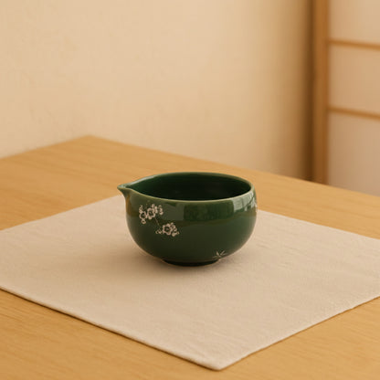 matcha green tea bowl​ with floral design on a beige surface