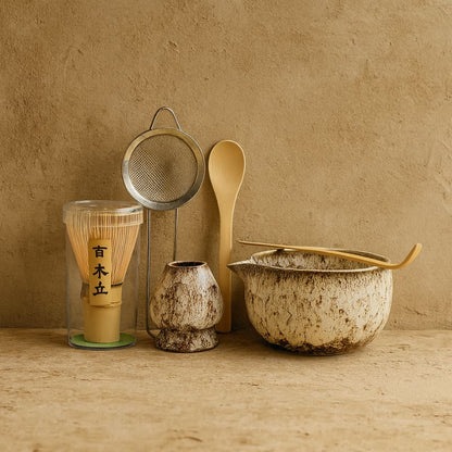 Tea-making matcha whisk set including a whisk, spoon, and bowl on a beige surface.