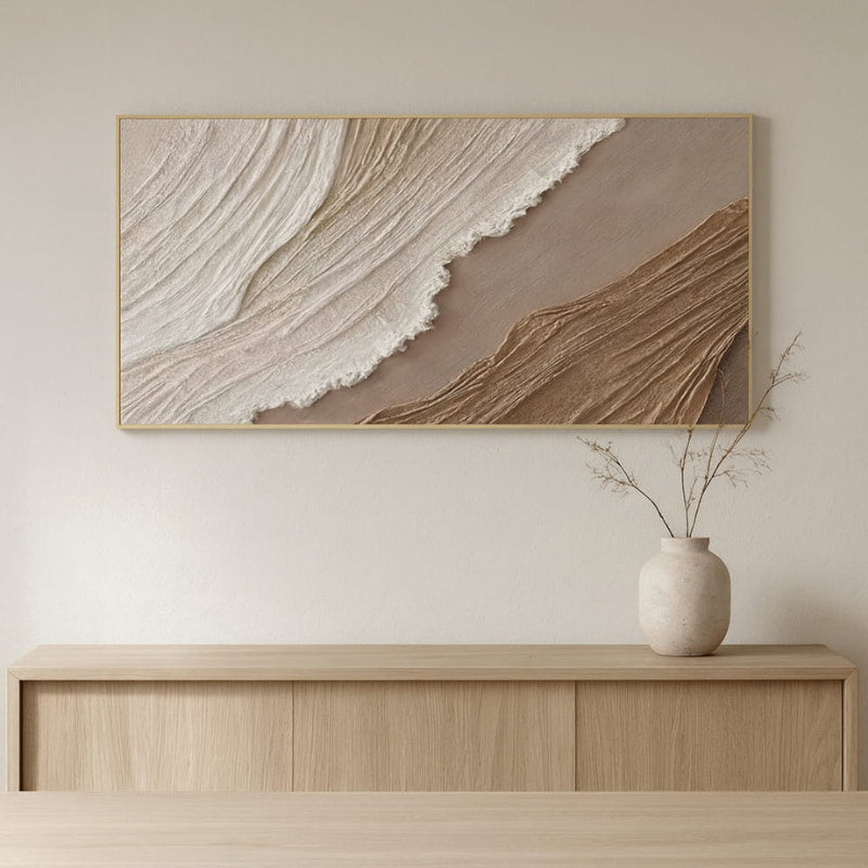 Minimalist beach painting on a wall above a wooden console table with a vase.