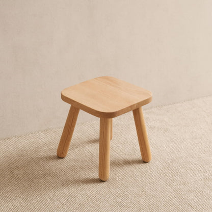 minimalist stool on a textured beige surface with a neutral background
