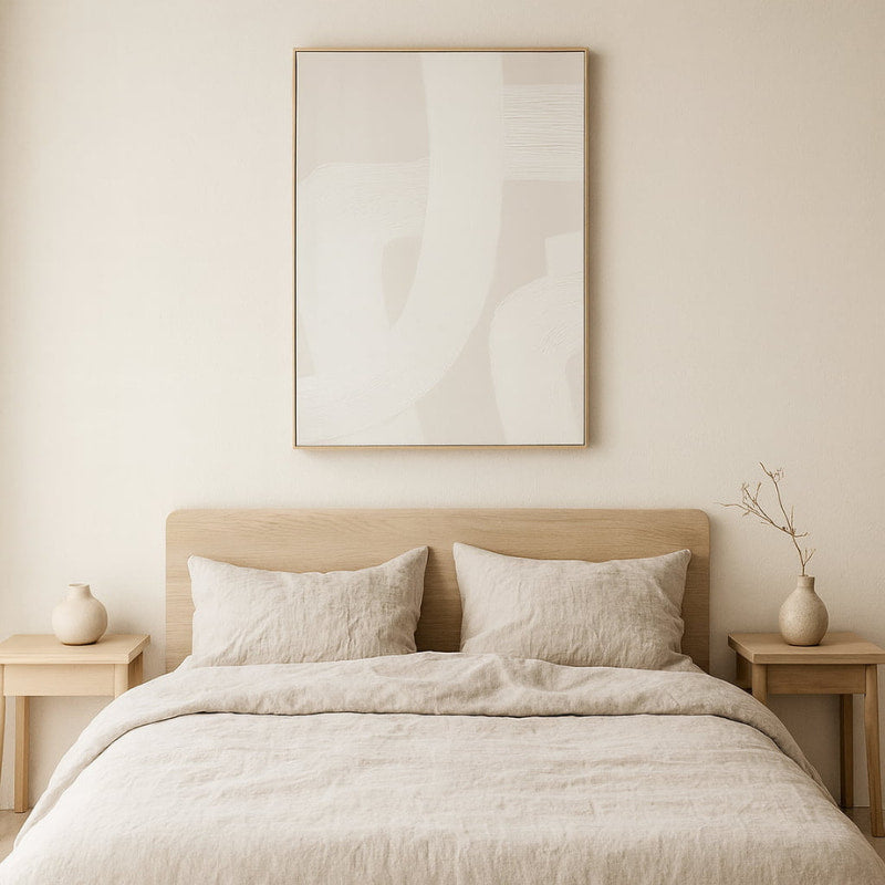 Neatly made bed with modern abstract wall art​ in a bedroom setting.