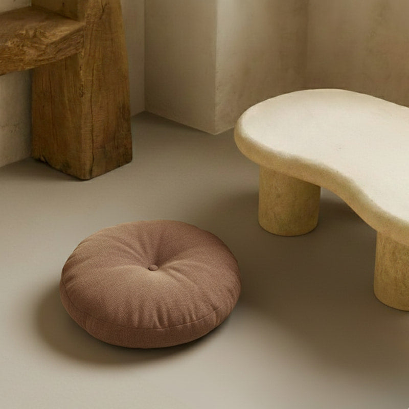 Round patio seat cushions​ on a light gray floor with a stone-like stool in the background.